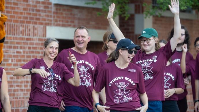 four faculty and staff cheering in Team Trinity move-in day shirts